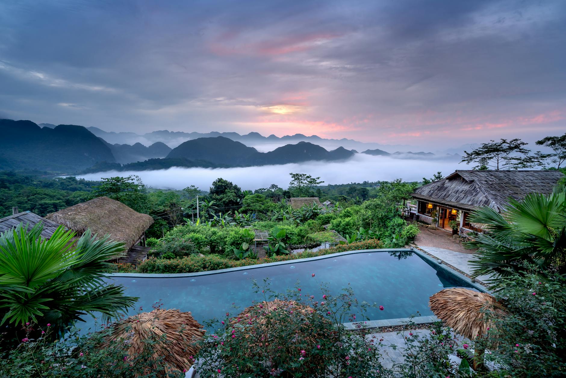 Stunning mountain resort view with pool and sunrise clouds, perfect for a peaceful getaway.