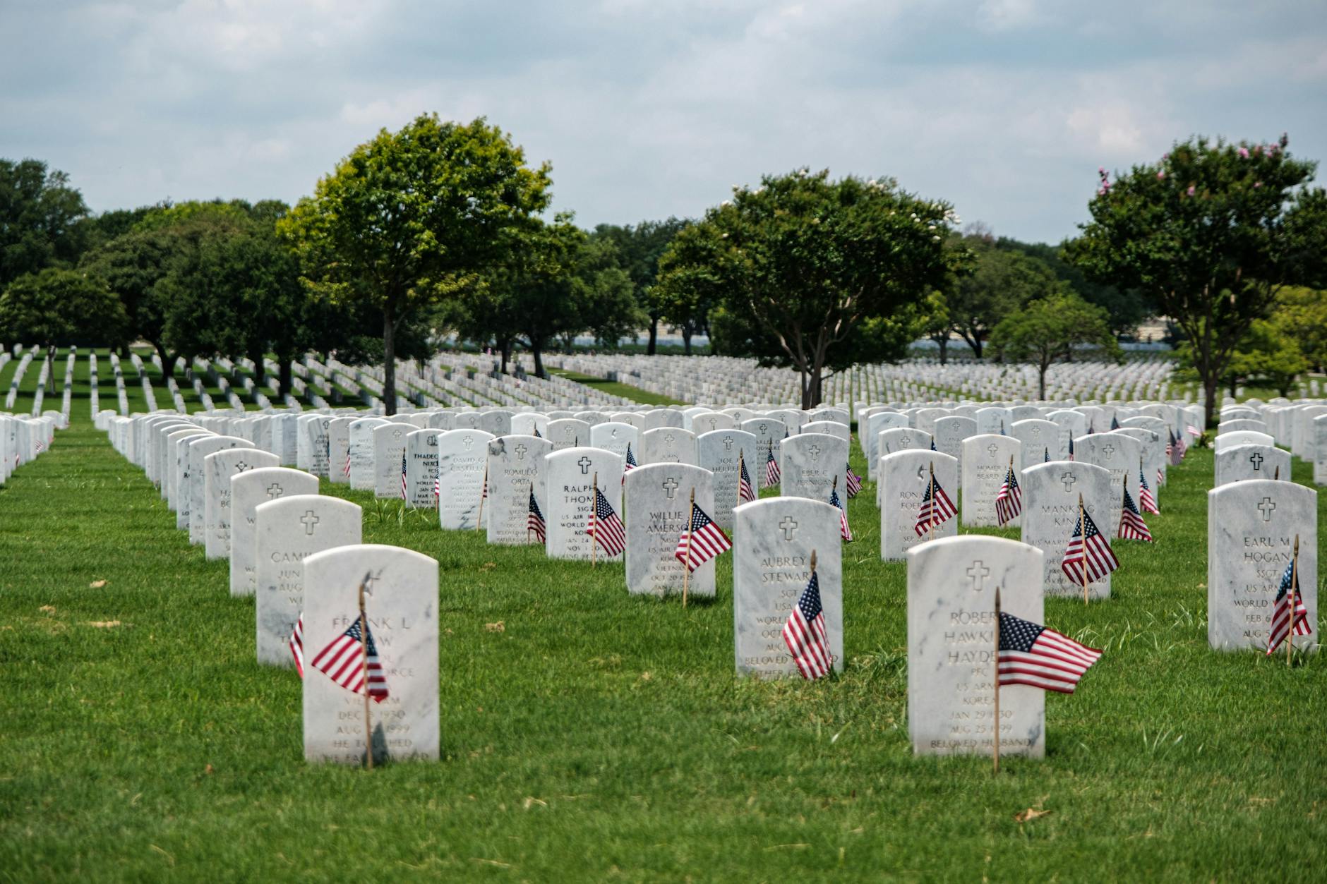 Gravestones with American flags at Fort Sam Houston National Cemetery, honoring Memorial Day.