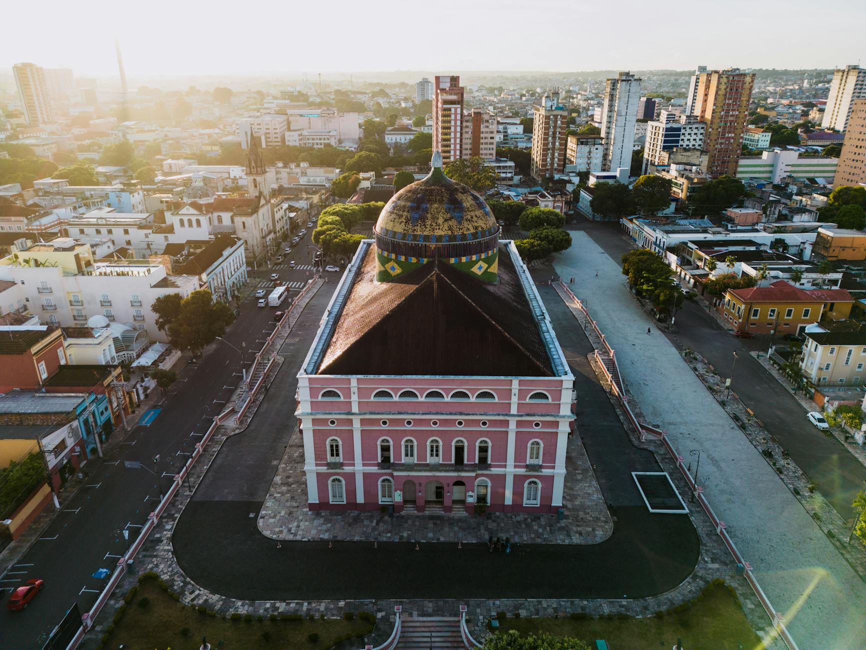 Aerial view of the iconic Teatro Amazonas in Manaus, Brazil, bathed in warm sunset light.