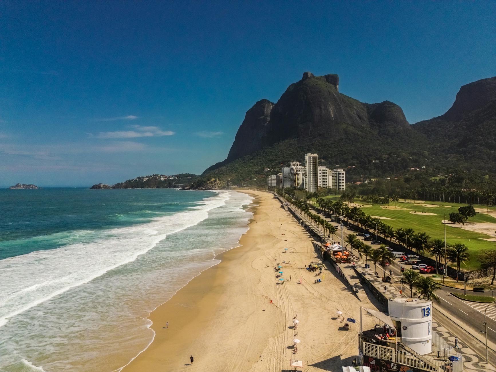 Stunning aerial view of Praia da Barra, Rio de Janeiro, featuring lush mountains and sandy shores.