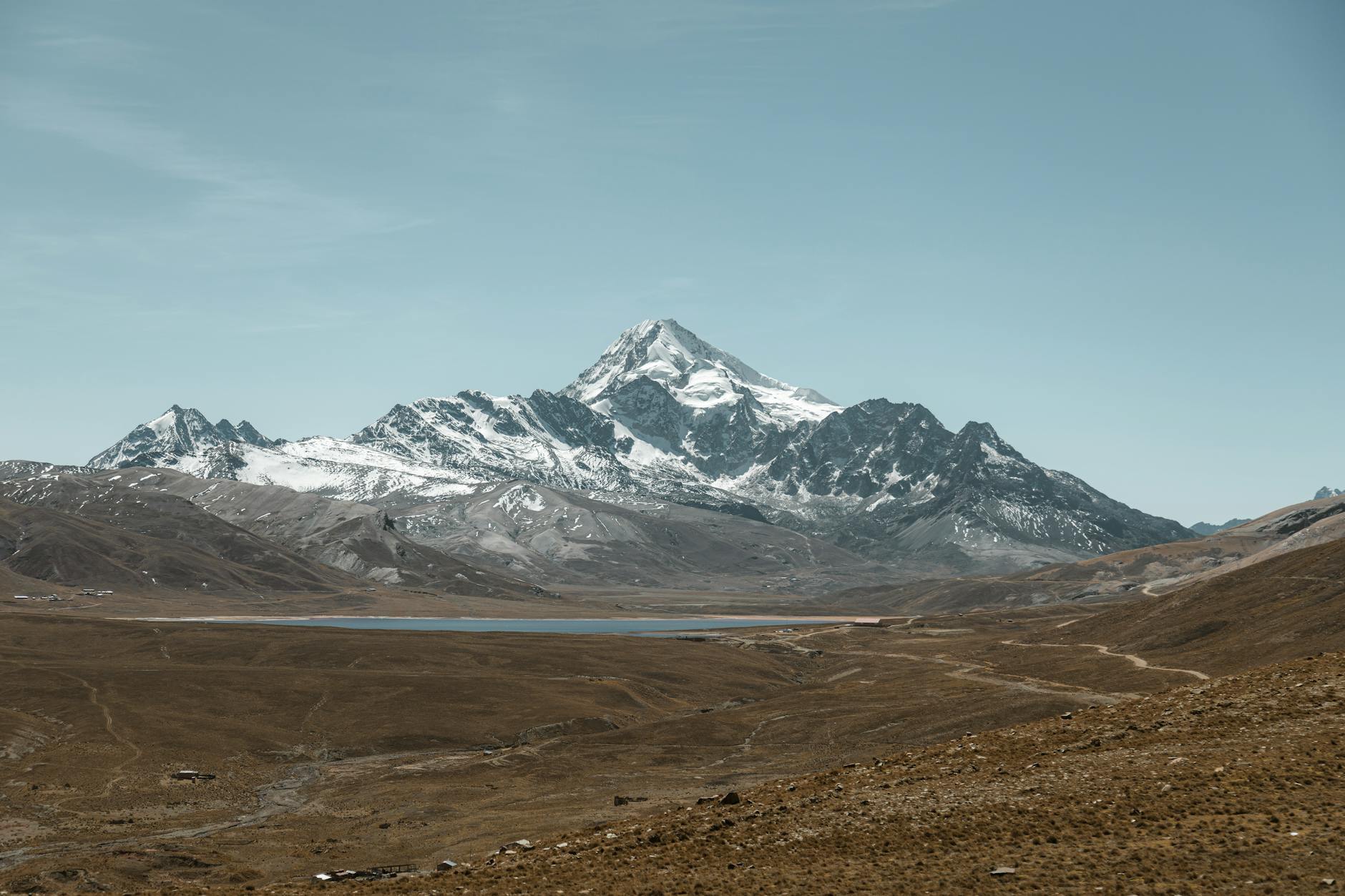 Explore the magnificent snowcapped Huayna Potosi mountain and serene lake in Bolivia's vast landscape.