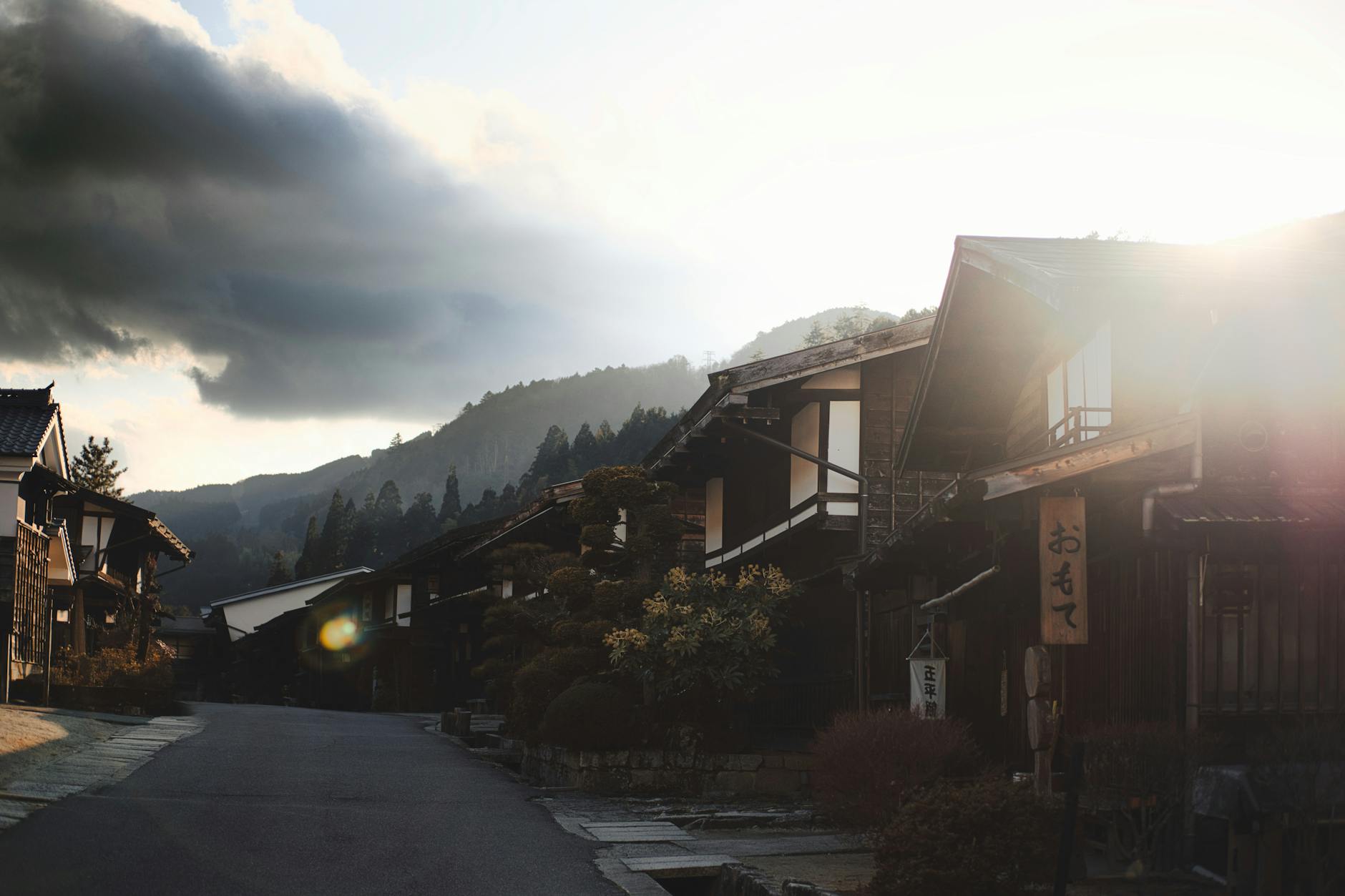Charming village scene in Japan with traditional homes and mountains at sunrise.