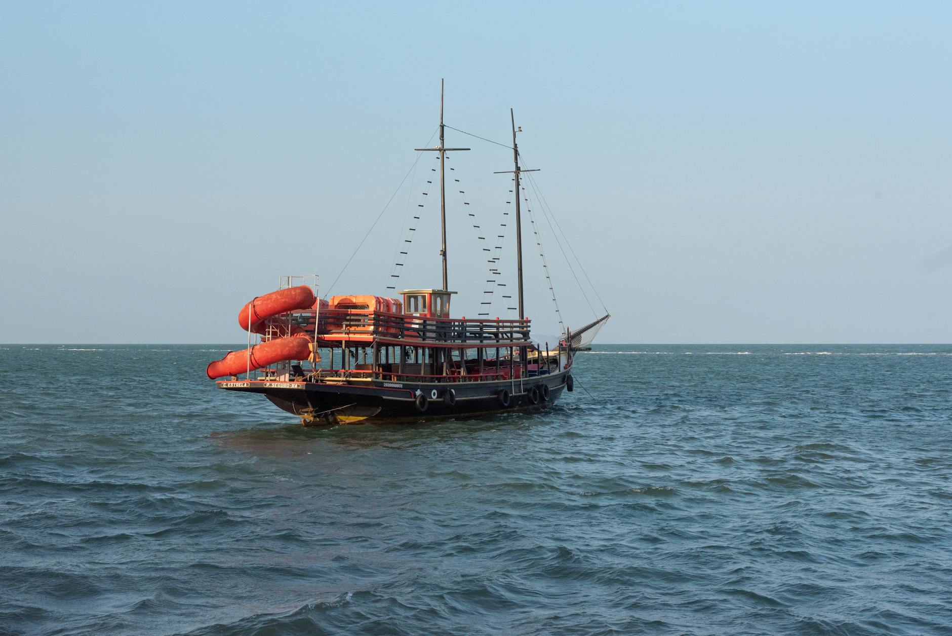 Tranquil scene of a wooden boat sailing on the ocean in Porto Seguro, Brazil with clear blue skies.