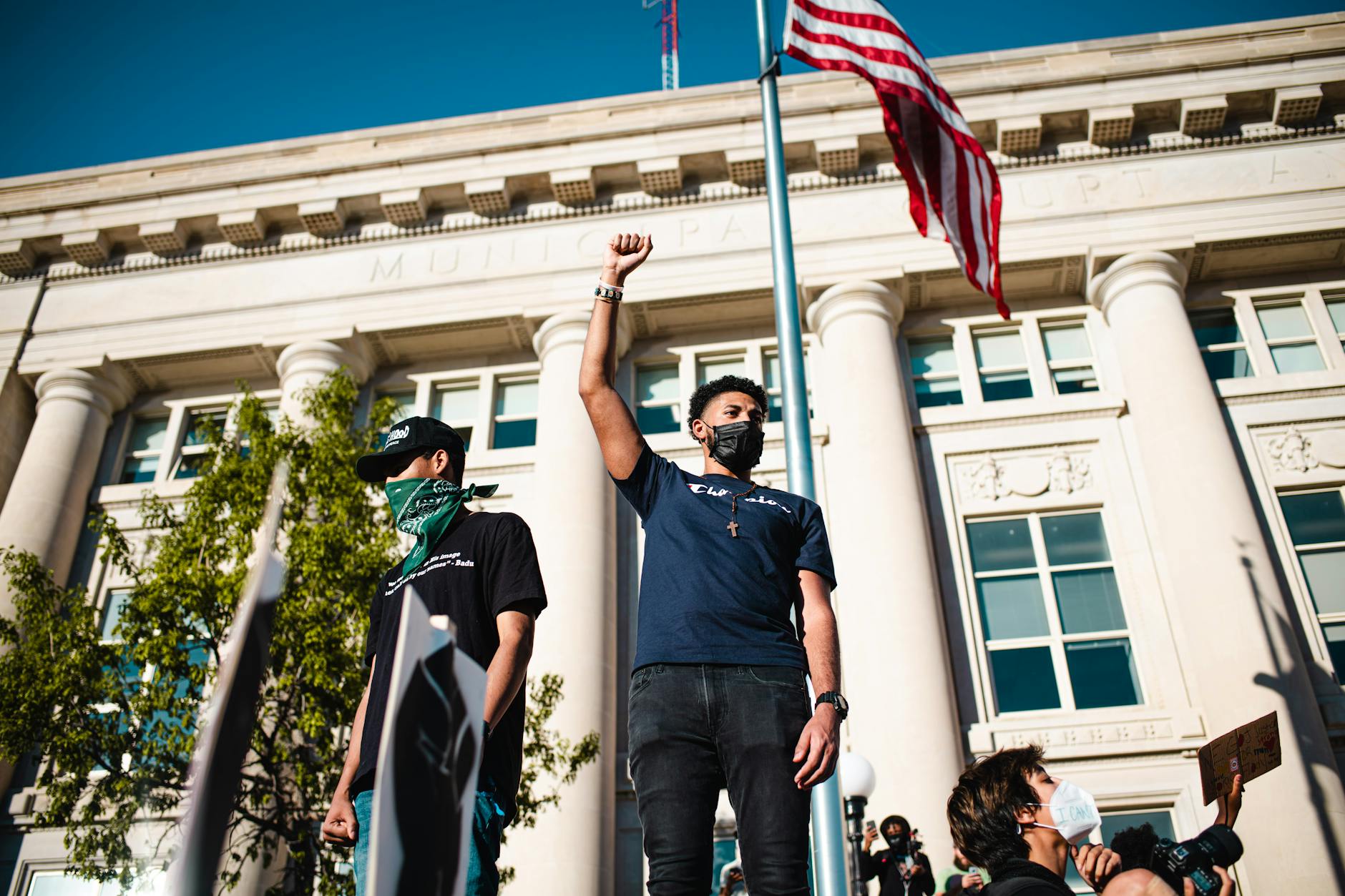 Protesters in Des Moines advocate for freedom with raised fists and American flag backdrop.