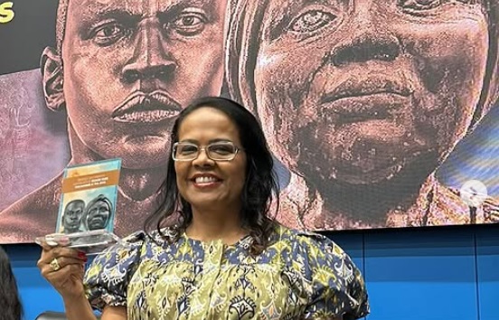 Retrato da desembargadora Jaceguara Dantas da Silva, mulher negra, sorrindo, em ambiente formal de tribunal.