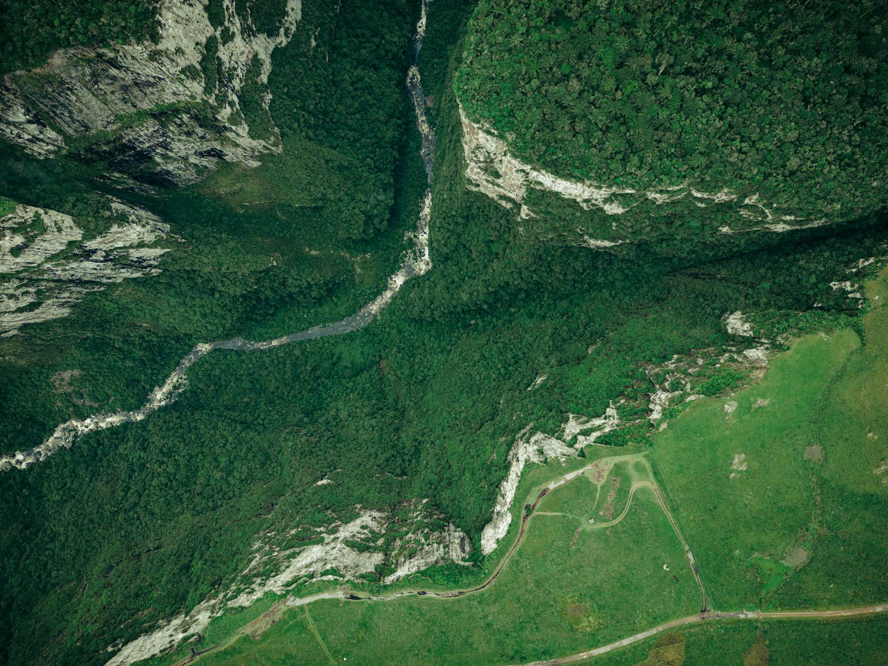 Breathtaking aerial shot of lush canyon landscape in Cambará do Sul, Brazil, showcasing dense forests and rugged rock formations.