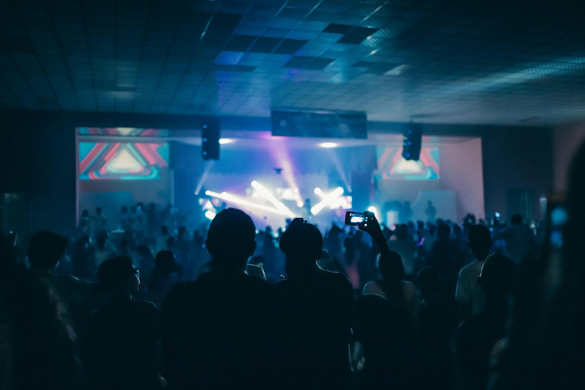 Vibrant indoor concert scene with a crowd enjoying live performances under dynamic stage lighting.