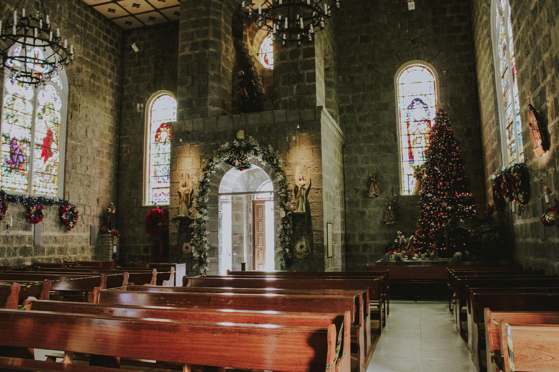 Interior of a beautifully decorated church in Gramado, Brazil, featuring Christmas trees and stained glass.