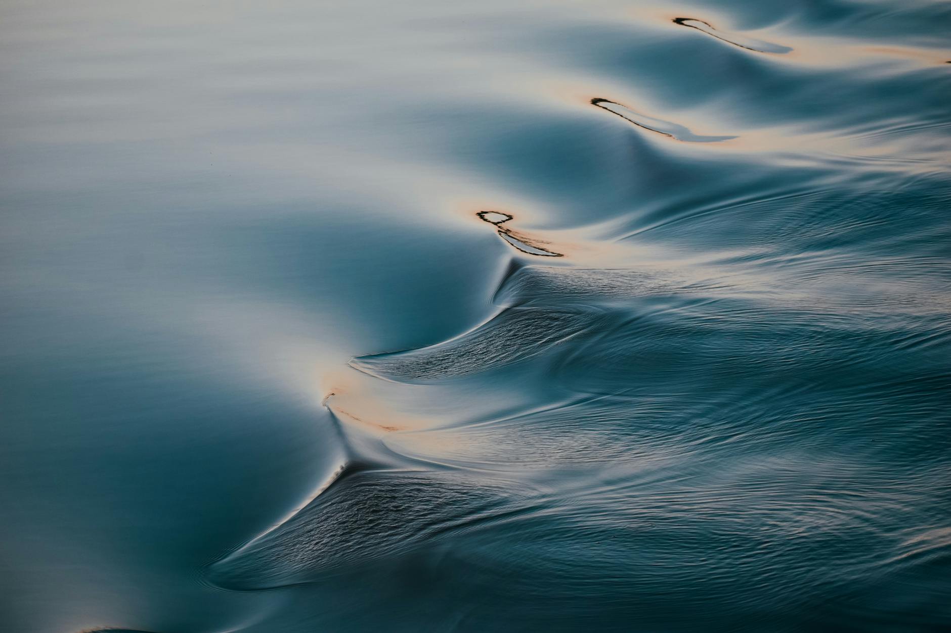 Serene close-up of gentle sea ripples reflecting twilight hues, showcasing fluid motion and tranquility.