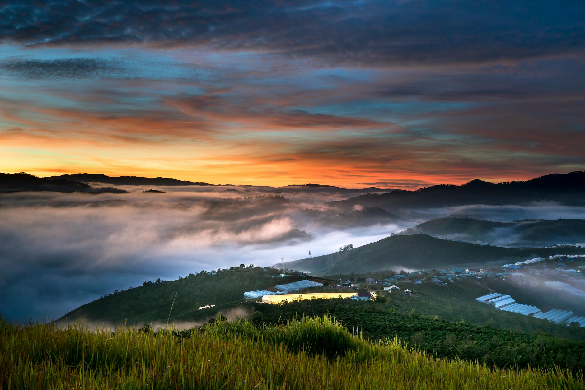 Breathtaking sunrise with mist covering a lush mountainous landscape, creating a serene atmosphere.