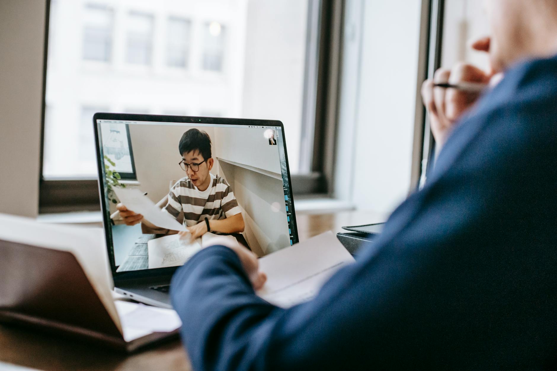 Two people engaged in an online class discussion through a video call on a laptop.